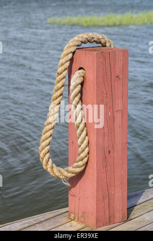 Rosso barca in legno bollard e fune sul bordo dock in legno Foto Stock