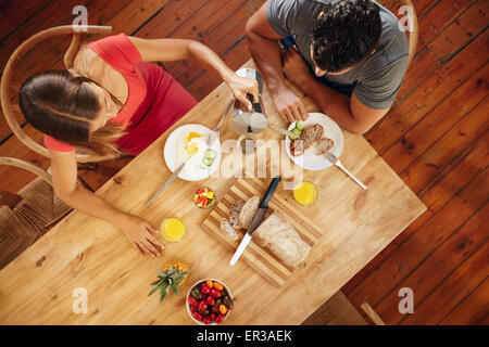 Vista aerea del giovane avente la colazione del mattino in cucina con la donna che serve caffè all'uomo. Foto Stock