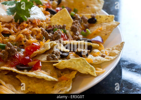 Mexican nachos con panna acida, olive nere, carne di manzo macinata, fagioli neri, pomodori, formaggio grattugiato, jalapenos, riso e coriandolo Foto Stock