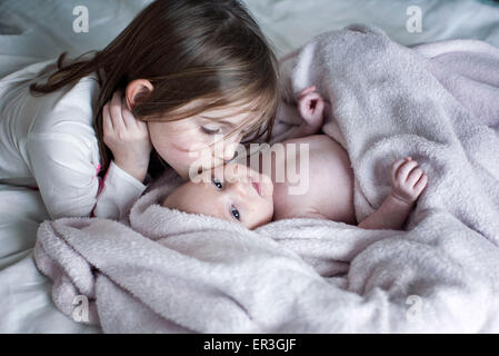 Little Girl kissing baby fratello sua guancia sul letto