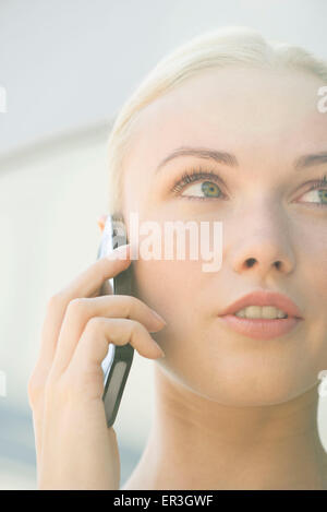 Donna che parla al cellulare con espressione seria sul viso Foto Stock