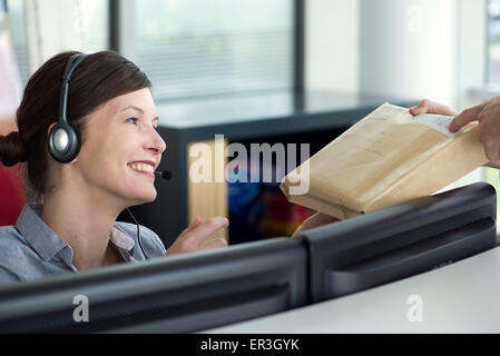 Receptionist che accetta il pacchetto da persona di consegna Foto Stock