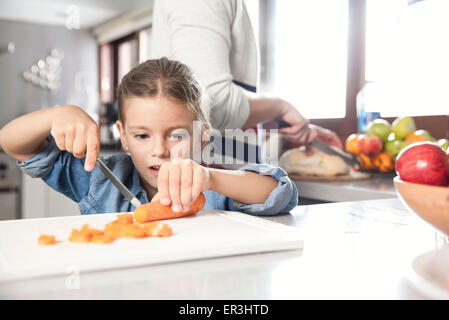 Bambina contribuendo a preparare il cibo in cucina Foto Stock