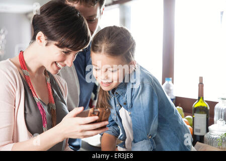 Famiglia guardando insieme allo smartphone Foto Stock