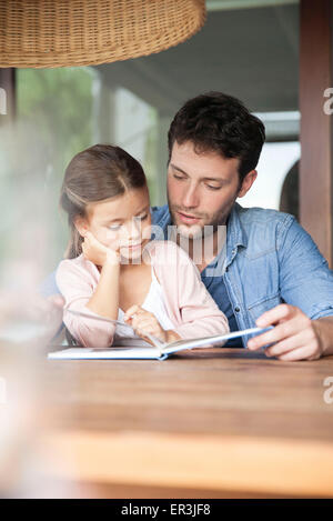 Padre e figlia giovane insieme di lettura Foto Stock