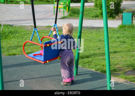 Adorabile bambina divertendosi su altalena per esterno Foto Stock