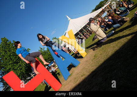 Festival di fieno, POWYS, GALLES - Maggio 2015 - Due giovani ragazze la lettura di libri sulla sommità del gigante segno di fieno sui prati del Festival in prima serata sun. Foto Stock