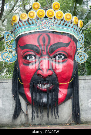 Un grande oriental faccia rossa con la statua di corona sulla parete Foto Stock