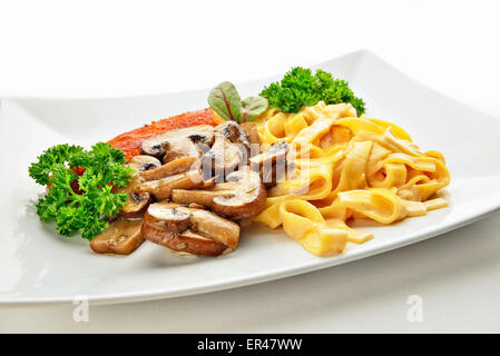 Cotoletta, pasta con panna fresca e funghi con rosmarino sulla piastra bianca closeup Foto Stock