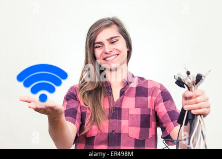 Giovani e ragazze felici è in possesso di Mazzo di cavi aggrovigliati nella sua mano. Simbolo Wifi visibile nell'altra. Foto Stock