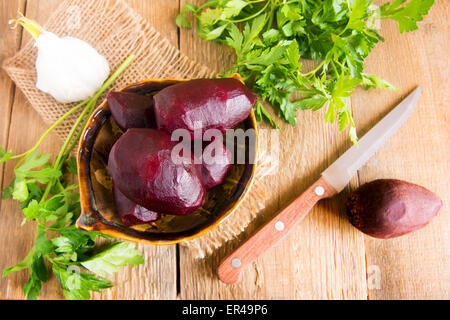 Bollito di barbabietole nella ciotola con il prezzemolo su tavola in legno rustico. Ingrediente della tradizionale cucina russa. Foto Stock