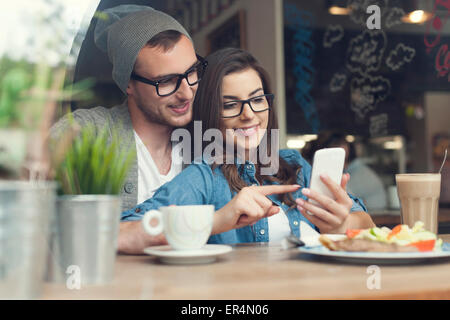 Abbracciando giovane utilizzando il telefono cellulare al cafe'. Cracovia in Polonia Foto Stock