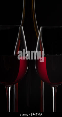 Rosso bottiglia di vino e due bicchieri di vino su sfondo nero Foto Stock