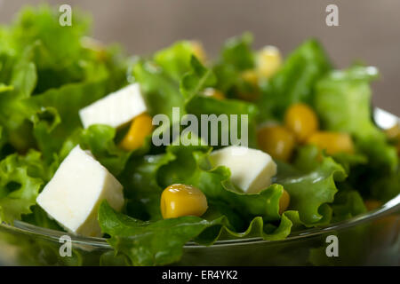 Insalata fresca con granturco dolce e formaggio in coppa sopra uno sfondo di legno Foto Stock