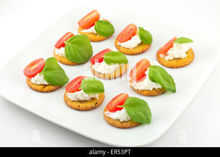 Piastra di snack di cracker conditi con pomodoro e basilico e ricotta Foto Stock