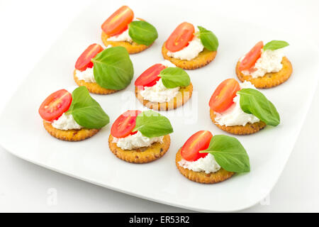 Piastra di snack di cracker conditi con pomodoro e basilico e ricotta Foto Stock