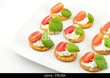 Piastra di snack di cracker conditi con pomodoro e basilico e ricotta Foto Stock