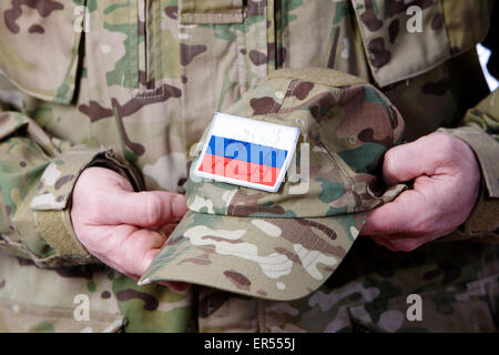 Uomo in combattimento fatiche holding esercito russo camouflage hat Foto Stock