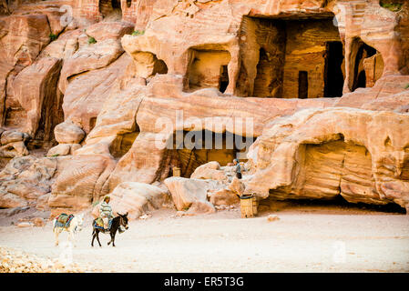 Uomo a cavallo di un asino che passa tombe rupestri, Petra, Giordania, Medio Oriente Foto Stock