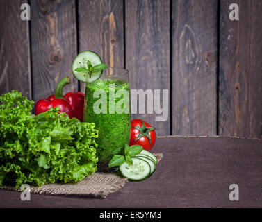 Fresco verde smoothie con il cetriolo, insalata verde, foglie di pomodoro e peperoni rossi a sfondo di legno Foto Stock