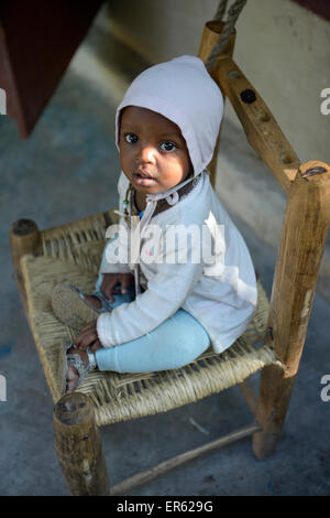 Bambino seduto su una sedia, Riviere Froide, Ouest Reparto, Haiti Foto Stock