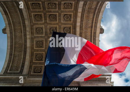 Tri-Color bandiera francese volare al di sotto di Arc de Triomphe, Parigi, Francia Foto Stock