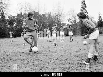 Queens Park Rangers calciatore Don Masson coaching i bambini a giocare a calcio a la Madonna degli Angeli Scuola di Crowthorne, Berkshire. Il 20 gennaio 1977. Foto Stock