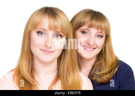 Giovani ragazze twins isolati su sfondo bianco. Allegro sorridente sorelle guardando dritto nella telecamera Foto Stock