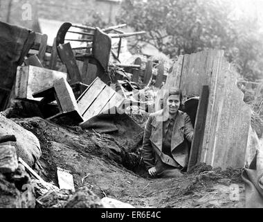 Una giovane donna emerge da un Anderson rifugio dopo un raid aereo e una pesante notte di bombardamenti. Circa: 1940 Foto Stock