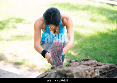 Sporty giovane donna stretching gambe all'aperto nel parco Foto Stock