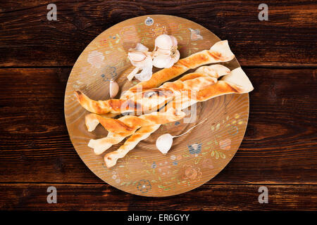 Pane Pizza con aglio sul piatto di legno su marrone vintage tavolo in legno, vista dall'alto. Pizzastick culinaria mangiare, rustico. Foto Stock