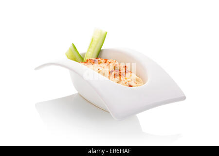 Hummus in bianco ciotola isolare su sfondo bianco. Il minimo di stile contemporaneo. Culinarie della cucina orientale. Foto Stock