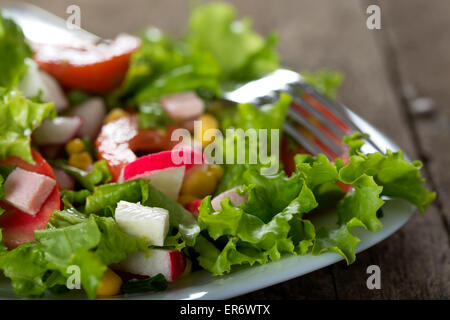 Insalata fresca con granturco dolce e formaggio nella piastra su uno sfondo di legno Foto Stock