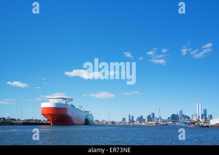 Grande nave da carico nel fiume Yarra con Melbourne CBD skyline in background. Foto Stock