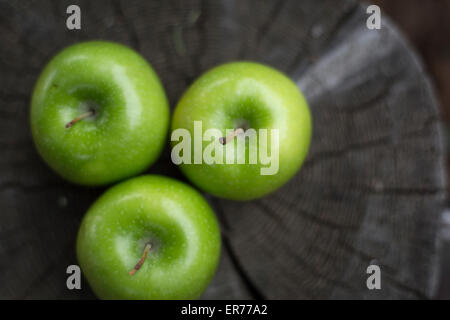 Tre mele verdi di sedersi su un di un moncone. Foto Stock