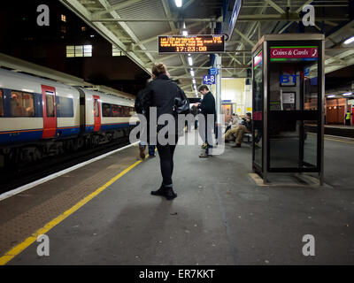 Passeggeri in piedi su una piattaforma a Woking station di notte Foto Stock