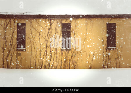 Giallo edificio abbandonato in un giorno di neve con imbarcati su windows e viti Foto Stock