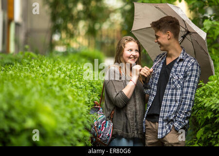 Un ragazzo e una ragazza divertirsi nel parco sotto un ombrello. Foto Stock