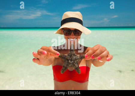 Una giovane donna può contenere fino a stella di mare mentre presso la spiaggia. Foto Stock