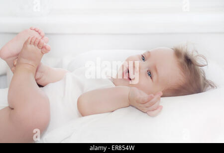 Piccolo grazioso happy baby boy giacente sul morbido cuscino bianco, happy family concept Foto Stock