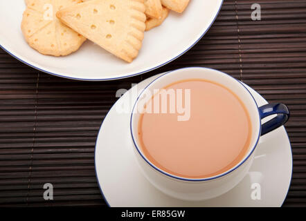Primo piano della tazza di tè con latte e piatto di biscotti frollini dall'alto Foto Stock