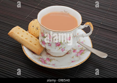 Primo piano di una tazza di tè con latte e biscotti frollini Foto Stock