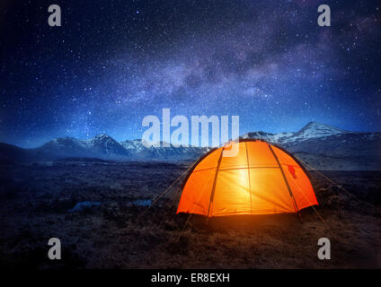 Una tenda da campeggio si illumina sotto un cielo notturno pieno di stelle. Campeggio Outdoor adventure. Foto Stock