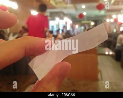 La copia in bianco spazio carta tag tenendo da parte delle dita. Una persona si siede in un ristorante cinese. Foto Stock