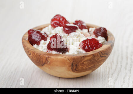 Formaggio con conserva di fragola in ciotola di legno su tavola in legno di quercia Foto Stock