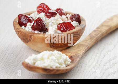 Formaggio con conserva di fragola in ciotola di legno su tavola in legno di quercia Foto Stock