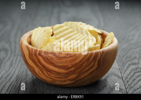 Increspata chip organico nella ciotola di legno sul tavolo di legno Foto Stock