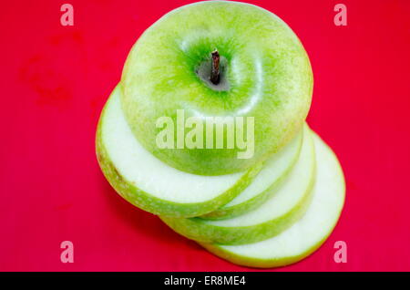 Apple in fette sottili pezzi contro uno sfondo rosso Foto Stock