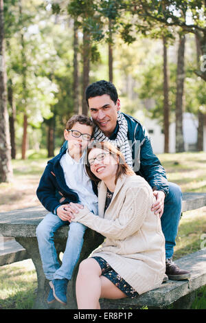 Ritratto di famiglia felice seduto sul tavolo da picnic in foresta Foto Stock