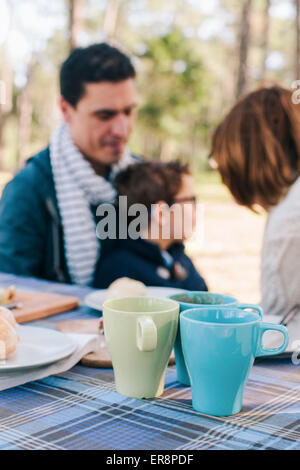 Famiglia seduti al tavolo per la colazione in foresta Foto Stock